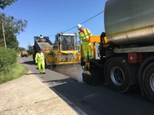 men and highways trucks surfacing the road