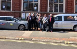 councillors and taxi representatives standing in front to two cars outside Eastbourne Town Hall