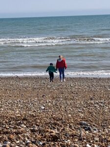 woman and child standing by the sea on a shingle beach