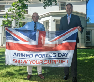 two men smiling holding a union jack flag with the words armed forces day at the bottom
