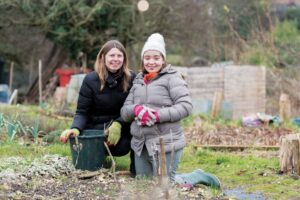 two laides kneeling whilst gardening