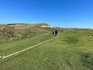 cliff top with people walking by a rope fence