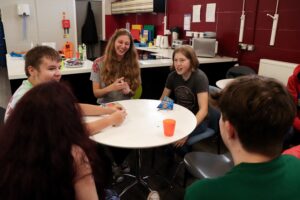 children sitting round a table laughing and talking to a woman