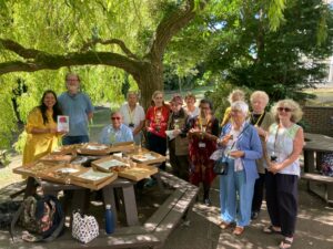 a group of older men and women smiling under a tree in the sunshine