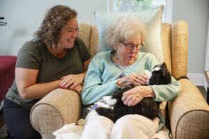 elderly lady sitting in a chair holding a mechanical cat 