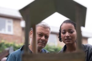 man and a young woman looking at a birdhouse